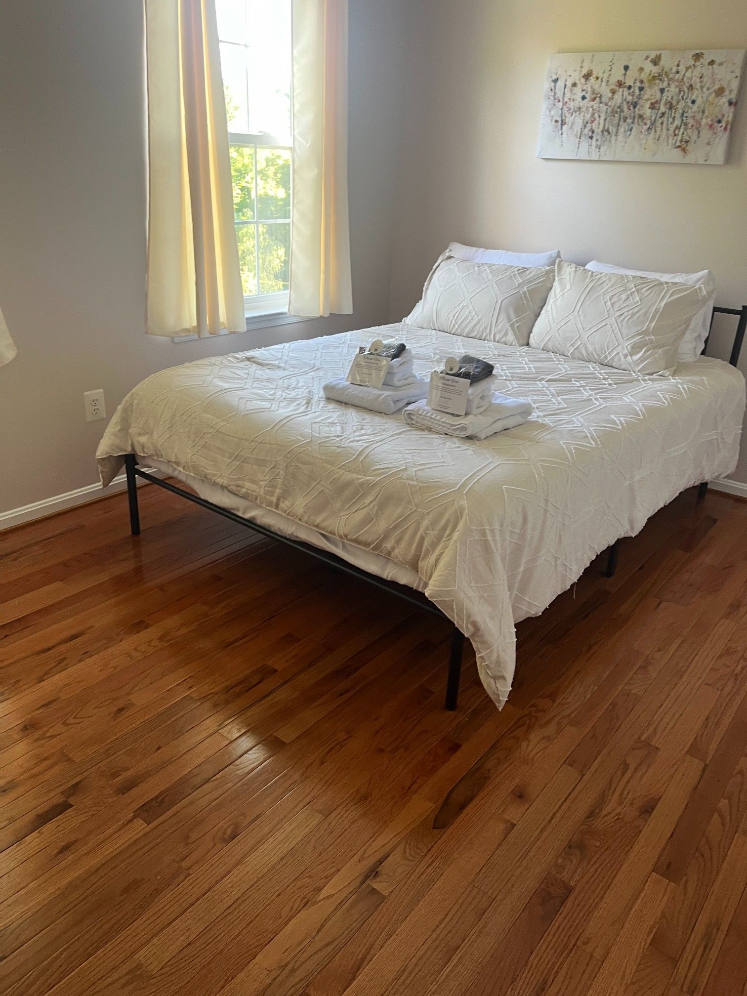 Bedroom with a bed, white bedding, hardwood floors, and a window.