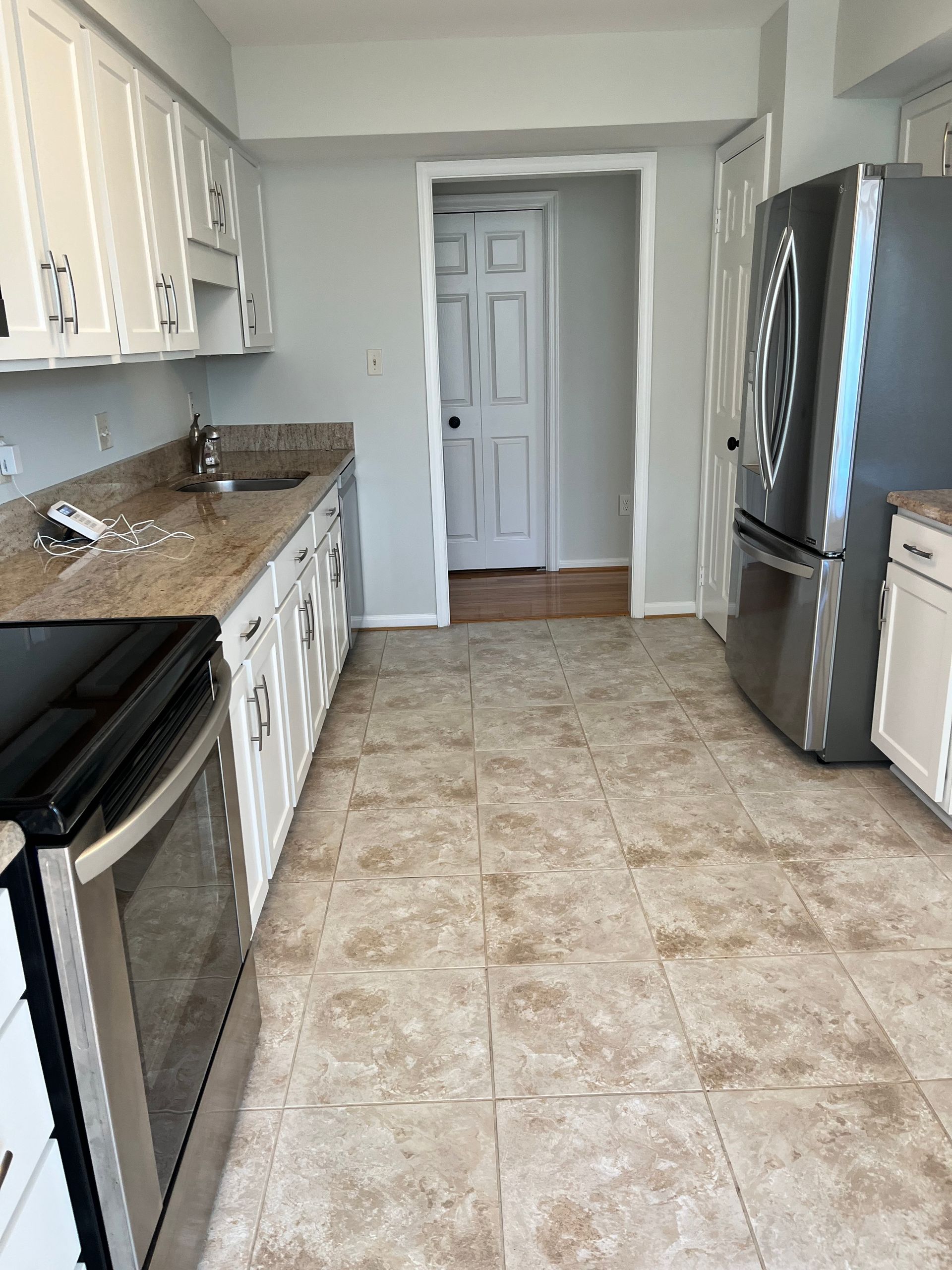 Kitchen with white cabinets, stainless steel appliances, and beige tile floor.
