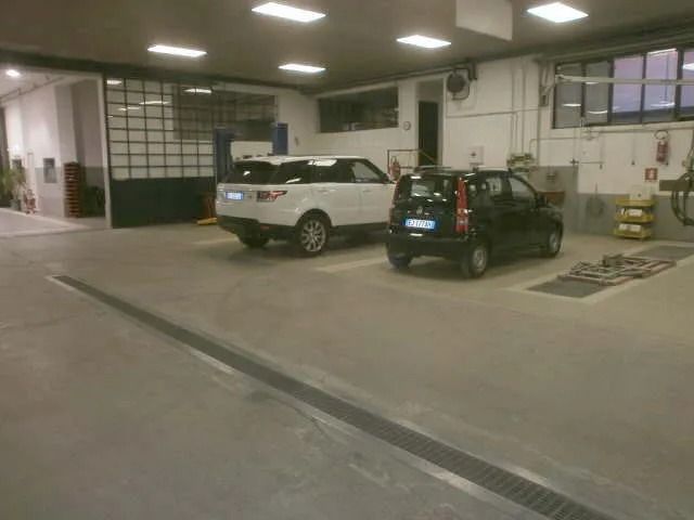 Un'officina con un SUV bianco e una berlina nera.