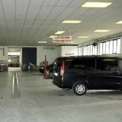 Furgone nero parcheggiato all'interno di un garage ben illuminato con le porte aperte.