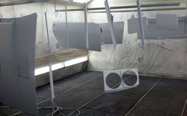 Parti di automobili in una cabina di verniciatura, preparate e pronte per la verniciatura.