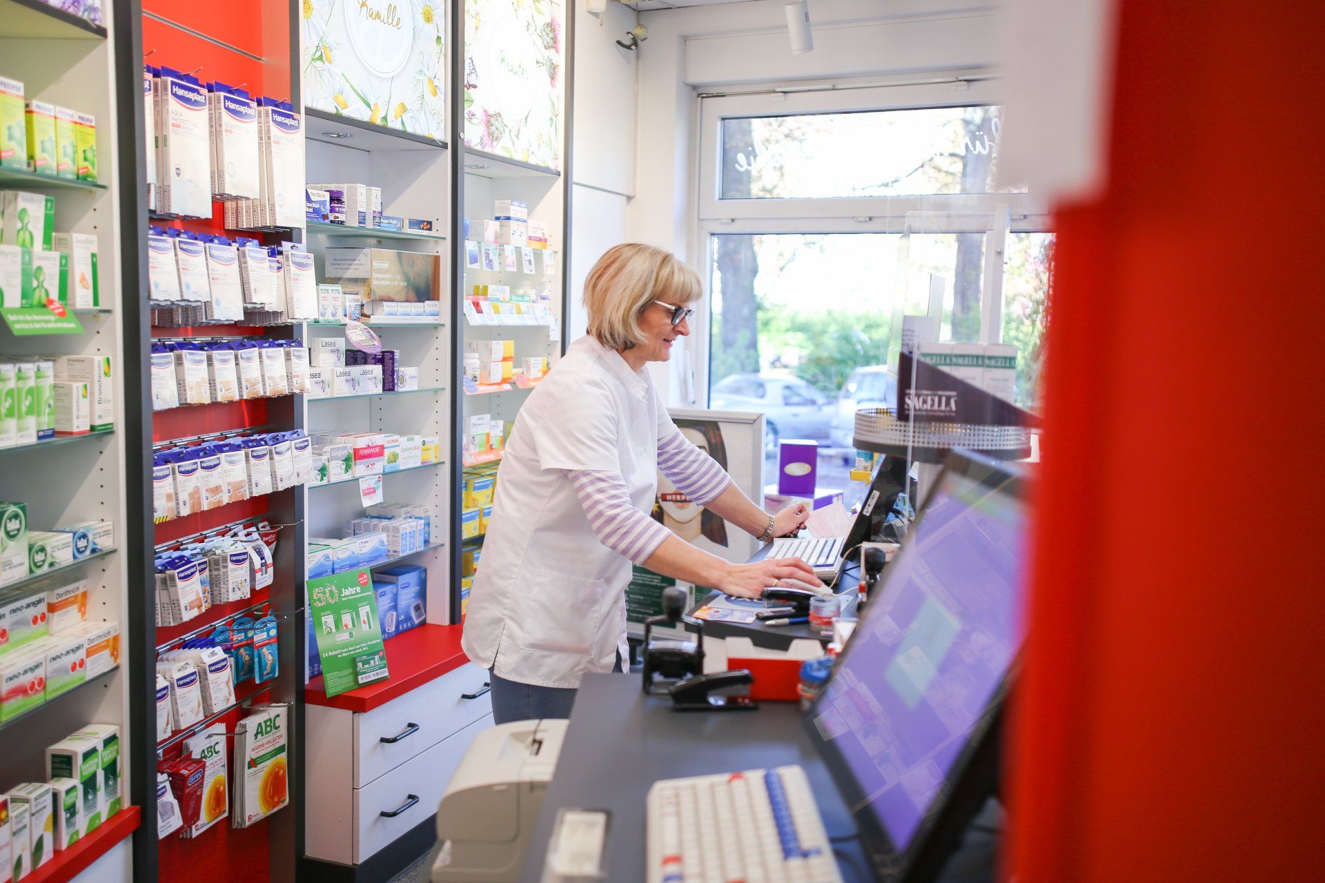 Eine Frau arbeitet an einer Theke in einer Apotheke.