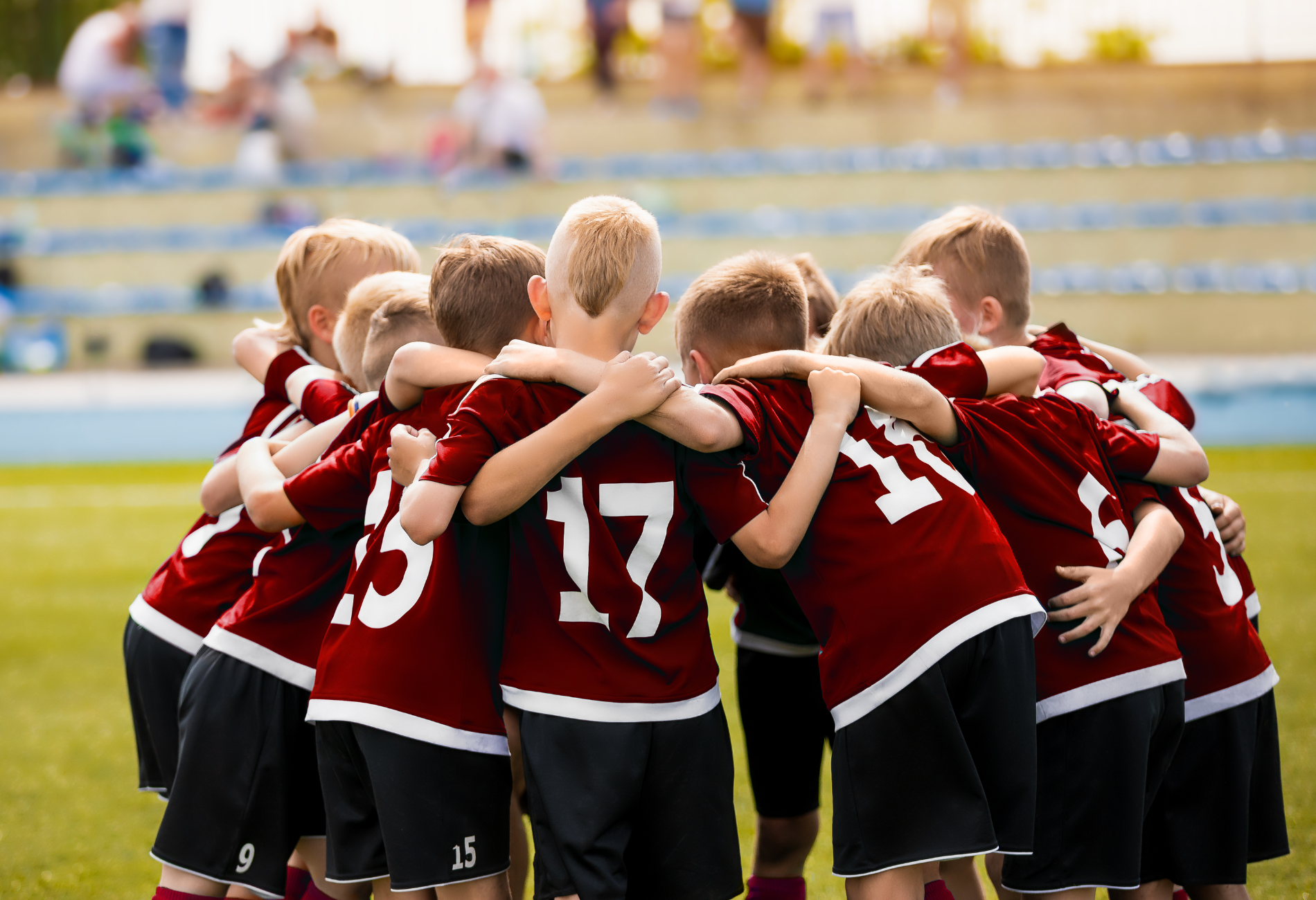 a group of young boys are hugging each other on a soccer field .