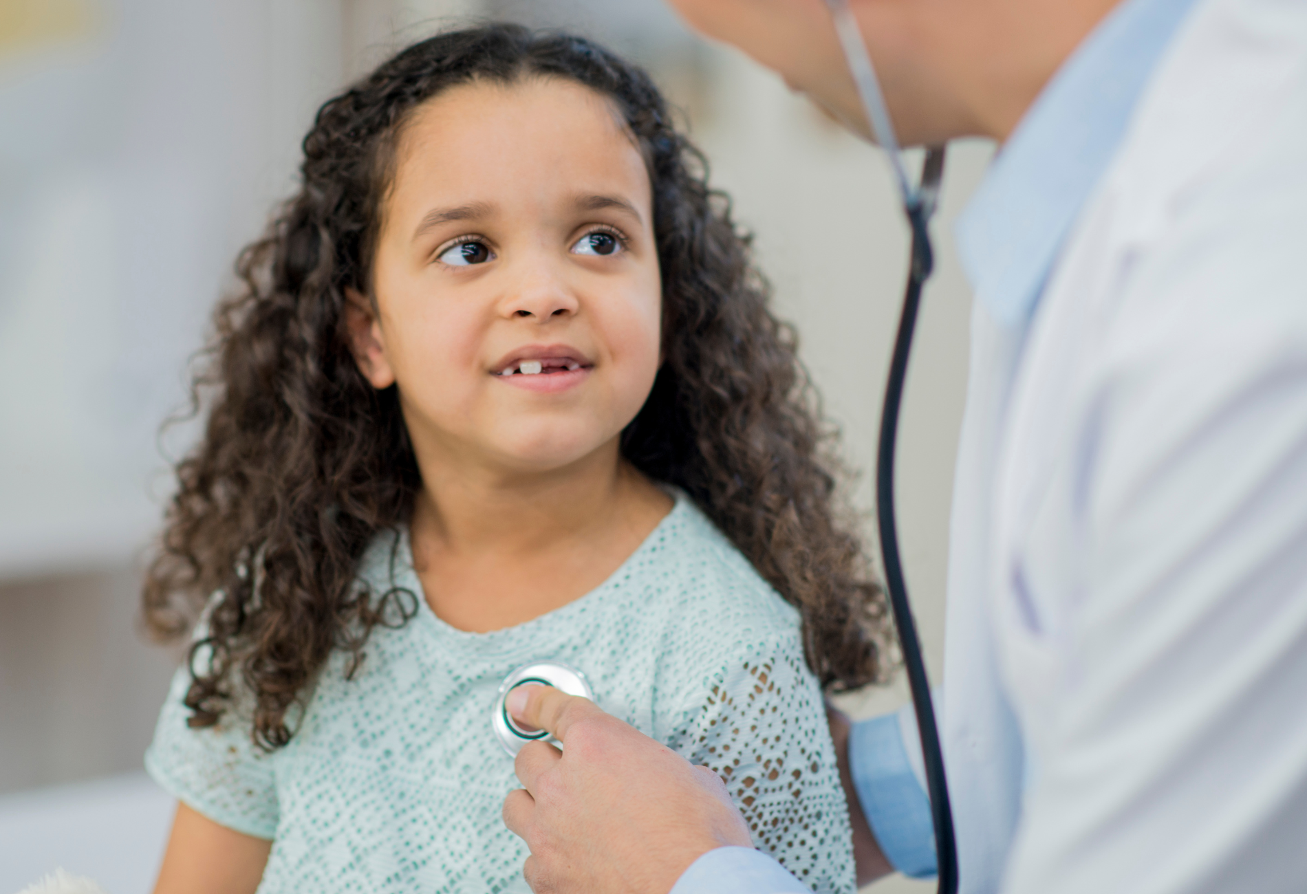 a little girl is being examined by a doctor with a stethoscope .