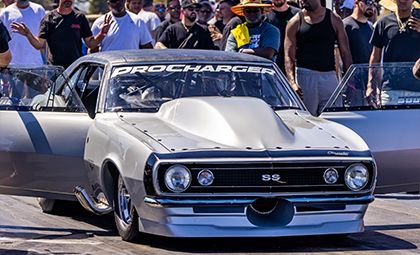 Silver drag racing car, doors open, preparing to race. 