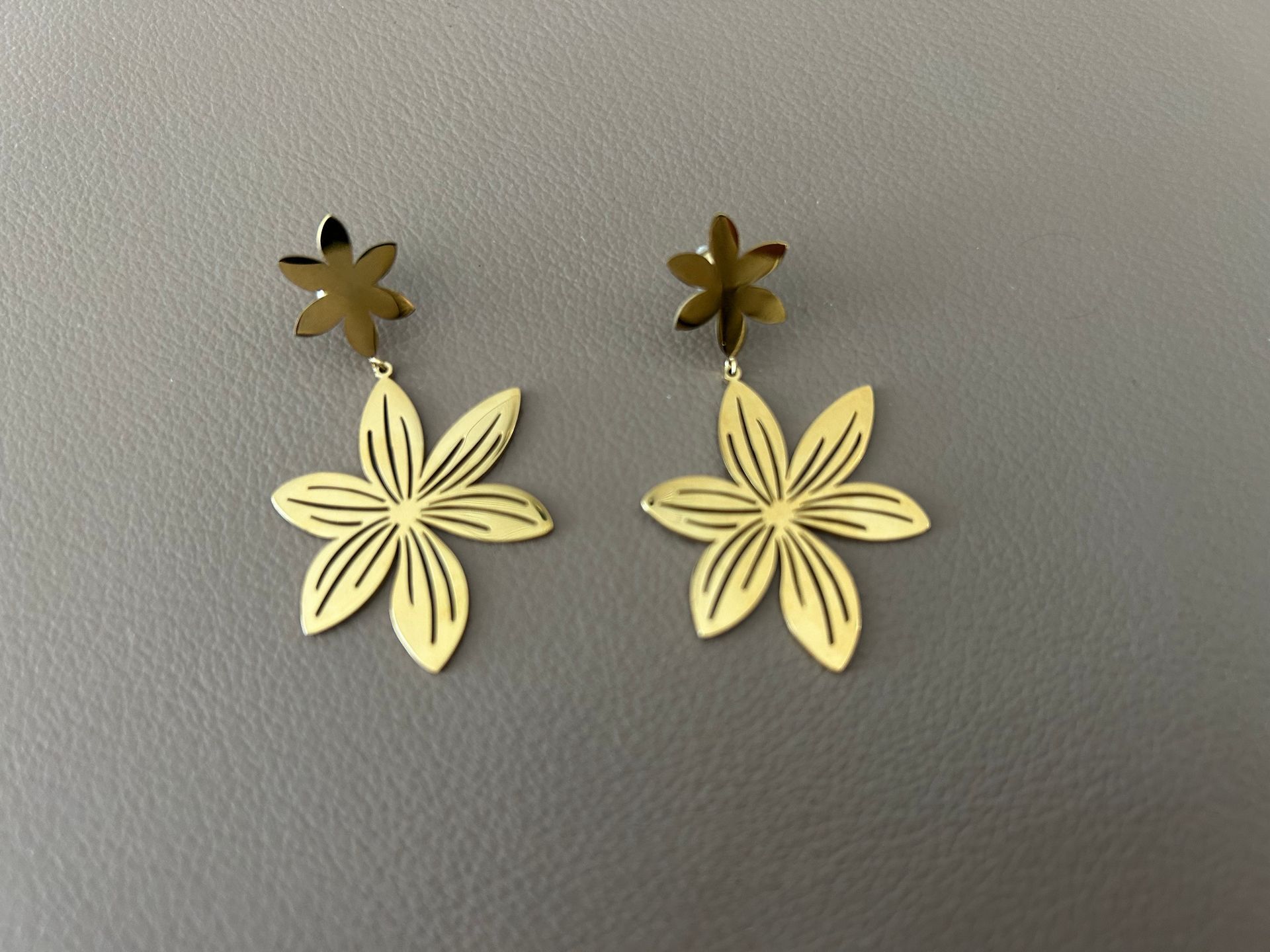 Gouden hangoorbellen met bloemmotief.