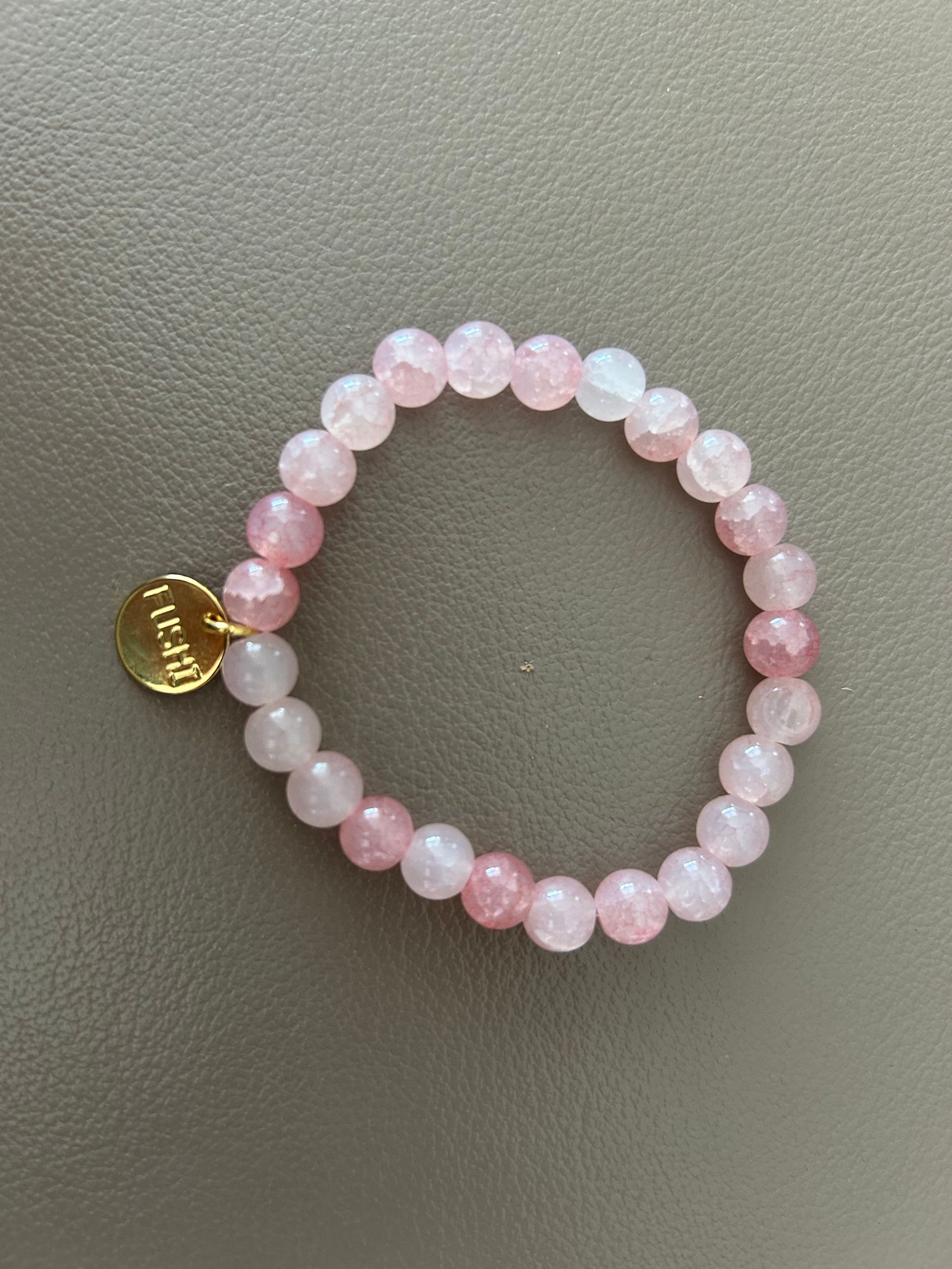 Glas kralenarmband roze met goudkleurig bedeltje van het merk.