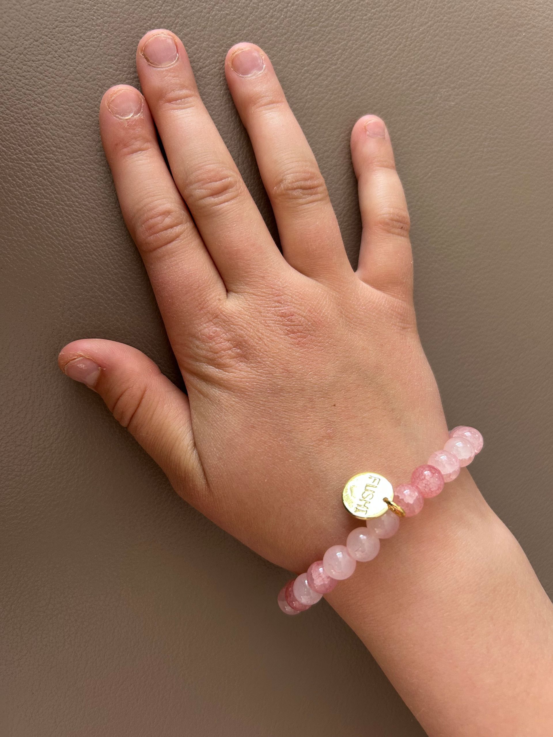 Glas kralenarmband roze met goudkleurig bedeltje van het merk.