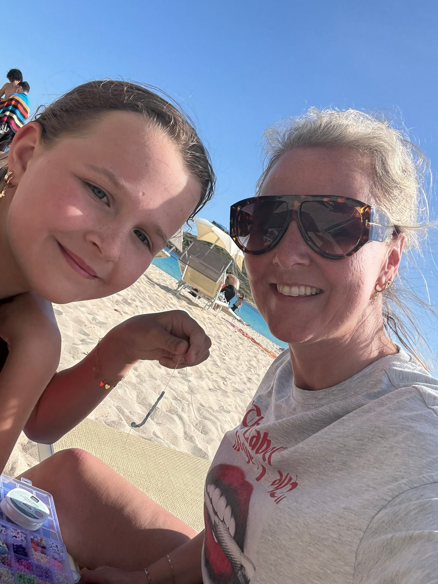Moeder Wanda en dochter Daniq samen sieraden makend aan het strand