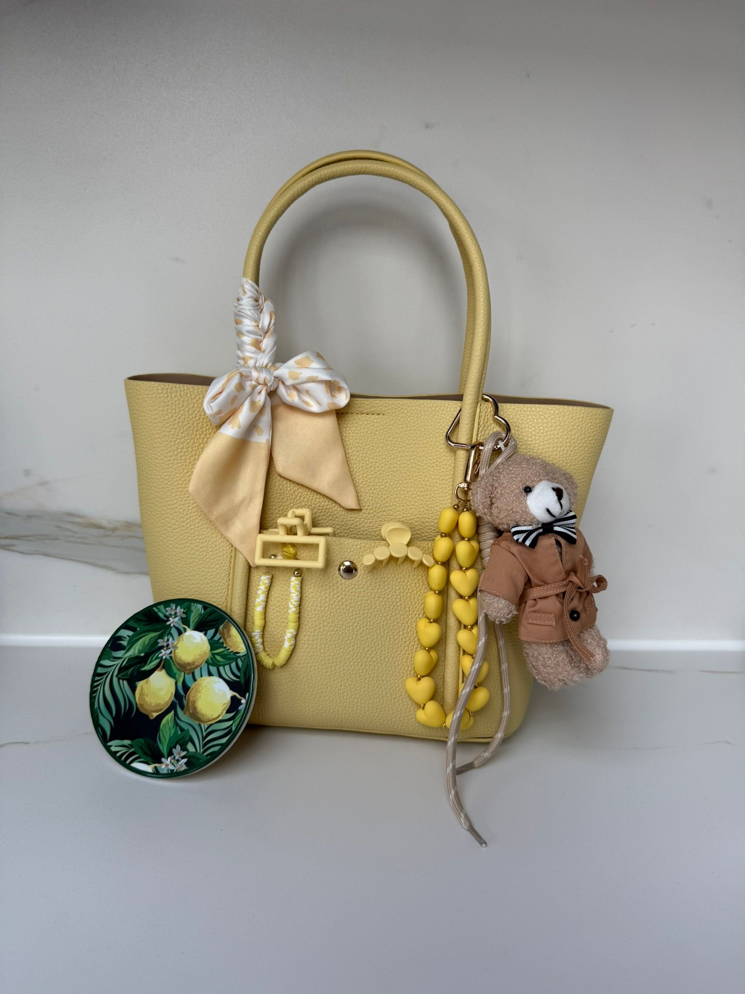De hit! Een gele handtas met bedeltje, teddybeeraccessoire, gestyled met citroen onderzetters en een telefoon koortje.