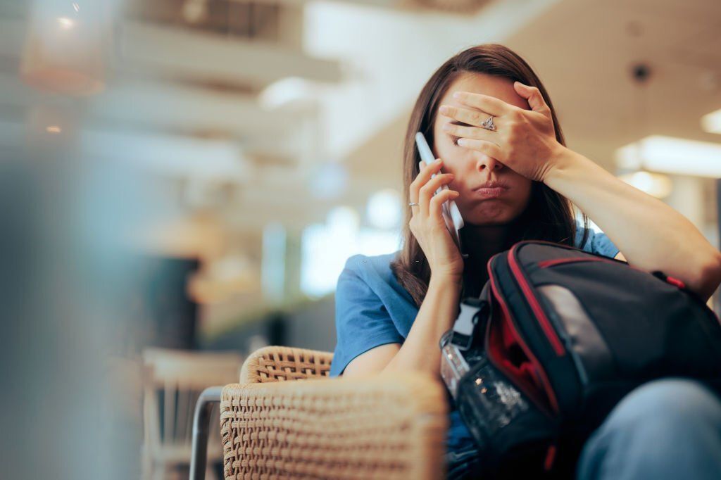 Stressed traveler speaking on her cellphone feeling overwhelmed.