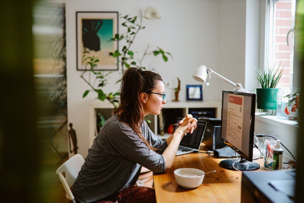 A woman sits in front of her computer while checking on her online booking.