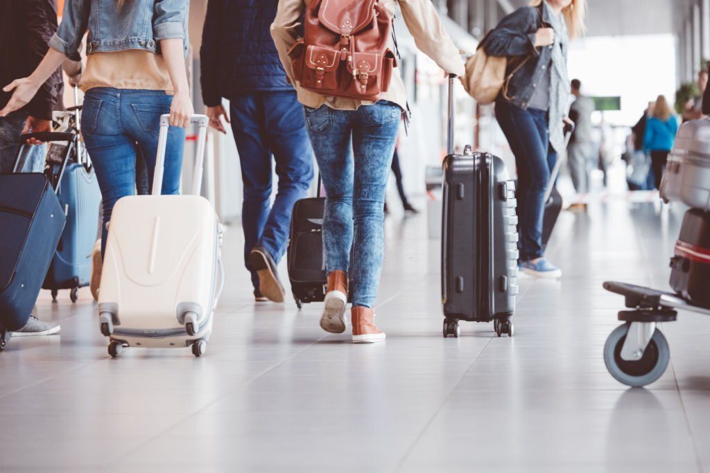 Low-angle rear view of passengers walking in the airport terminal.