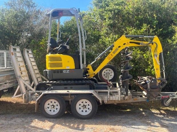 A Yellow Excavator is Parked on a Trailer — Mini Digger and Trailer Hire in Mareeba, QLD
