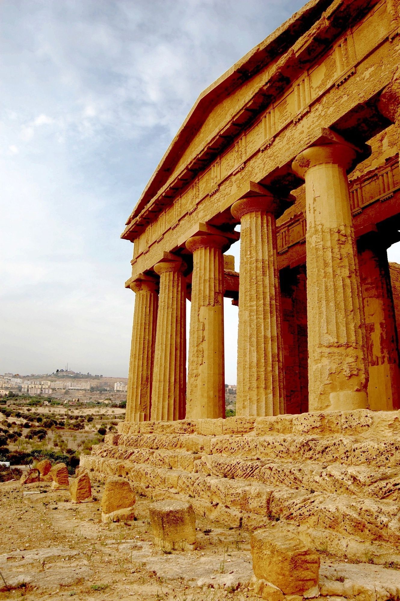 Ancient stone temple ruins with tall columns under a clear sky, overlooking a distant landscape