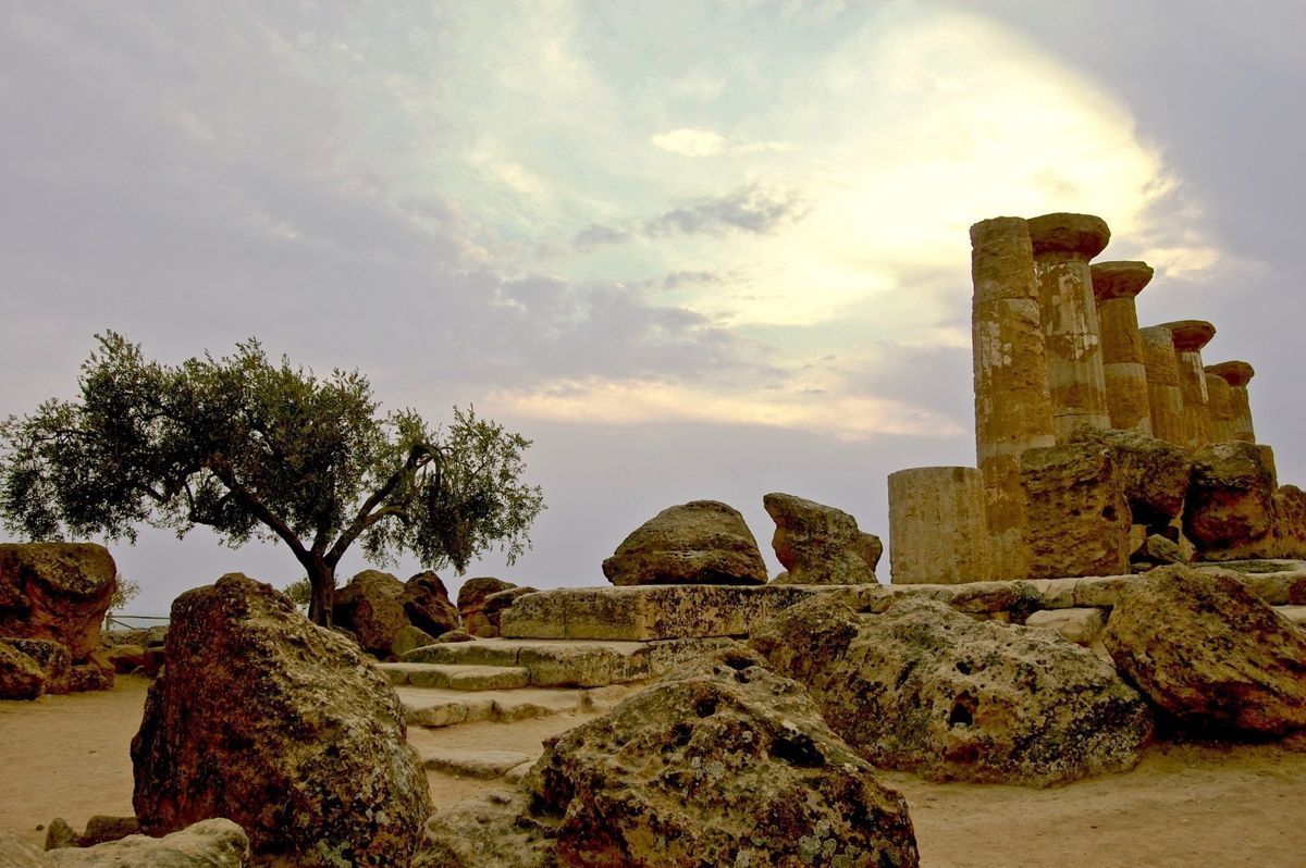Ancient stone ruins amid rocks and trees under a cloudy sunset sky