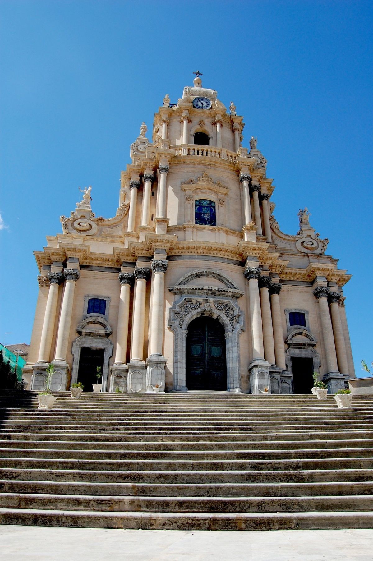 Ornate historic church facade with wide stone steps under a bright blue sky