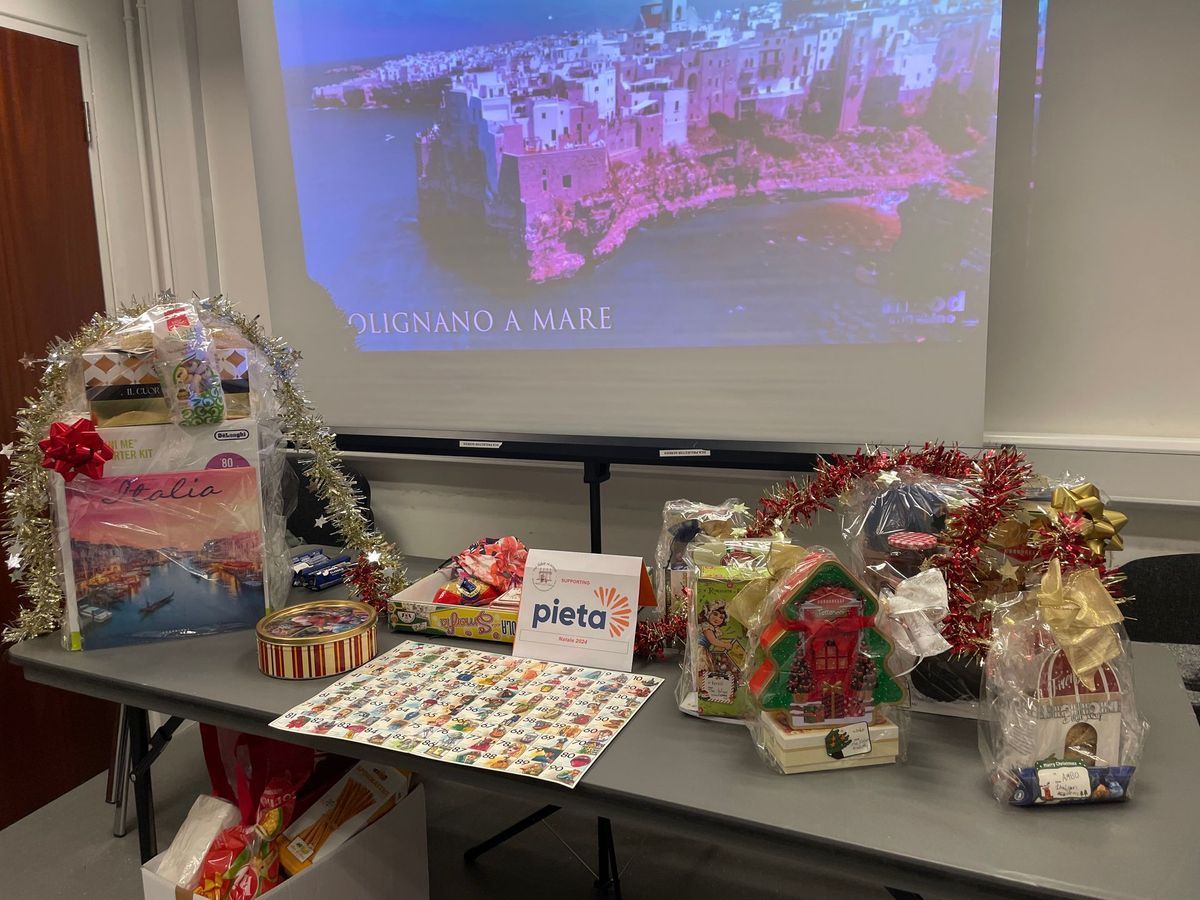 Holiday gift display on table beside projector screen with cityscape image and tinsel decorations
