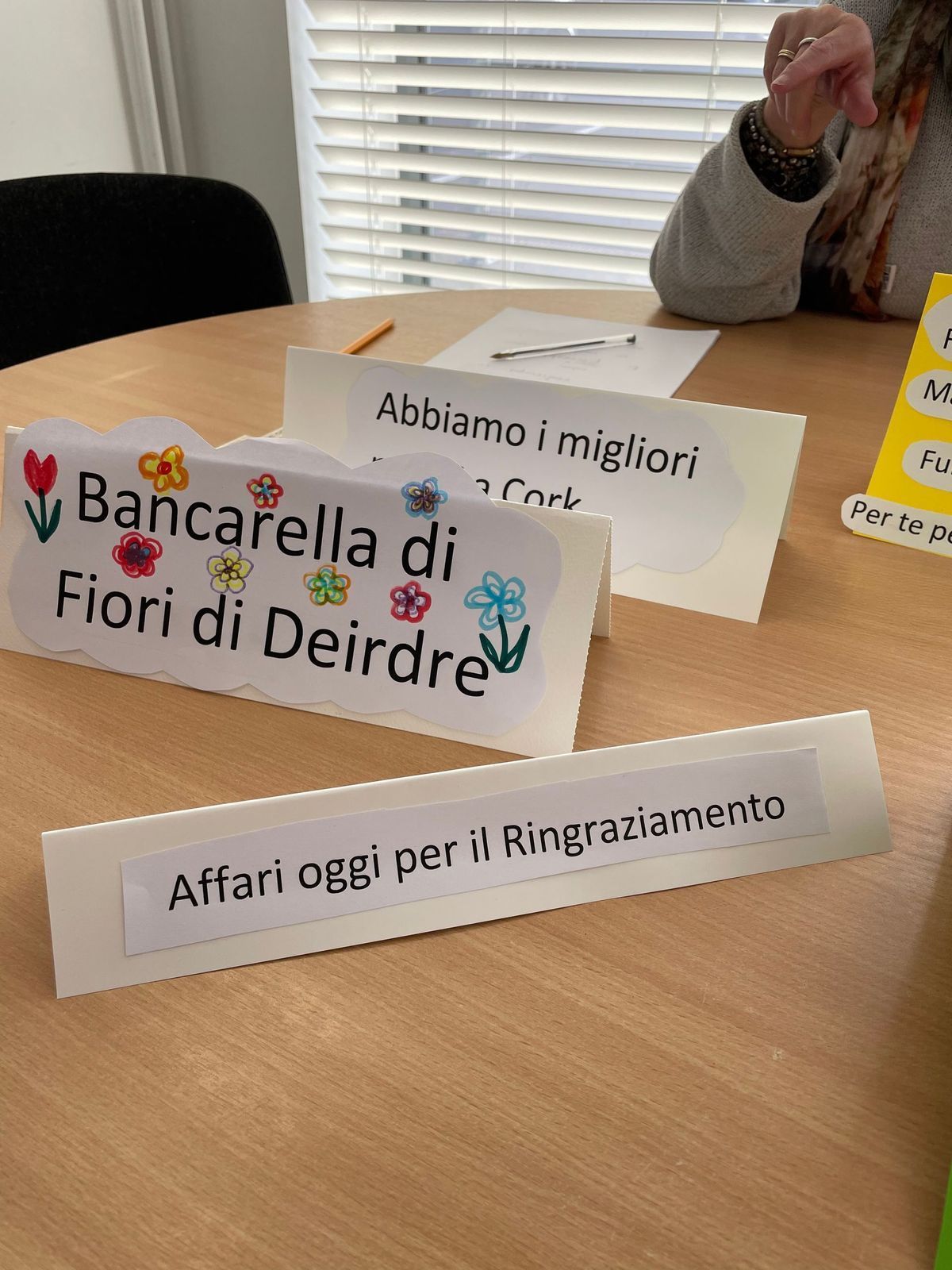 Table with handwritten Italian signs for “Bancarella di Fiori di Deirdre” and “Affari oggi per il Ringraziamento”