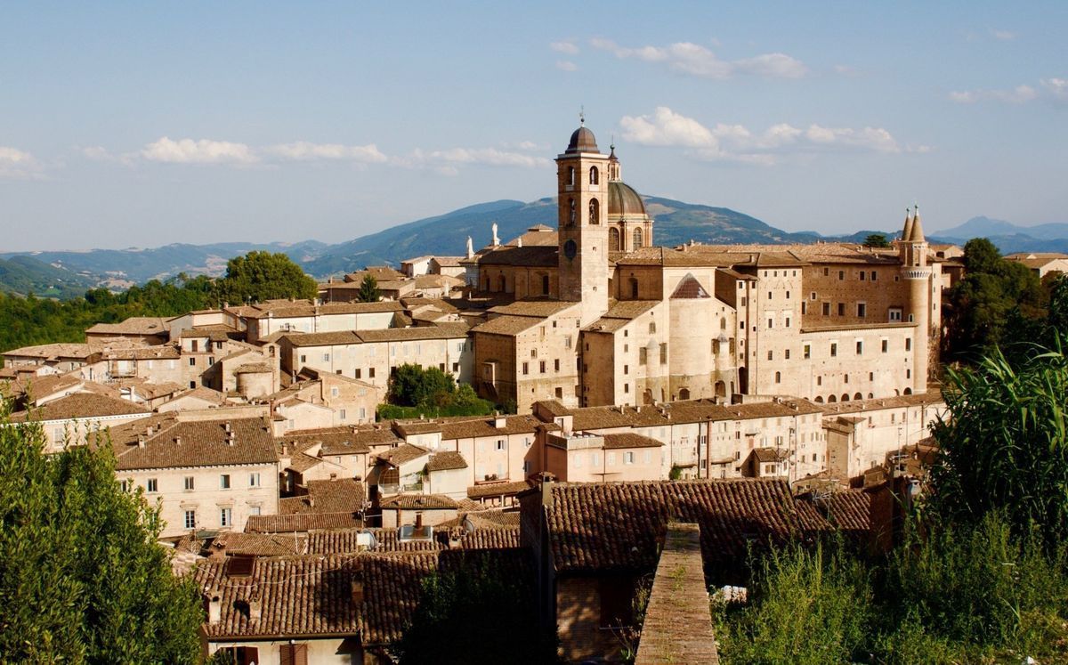 Hilltop town with beige stone buildings and a church tower under a clear blue sky