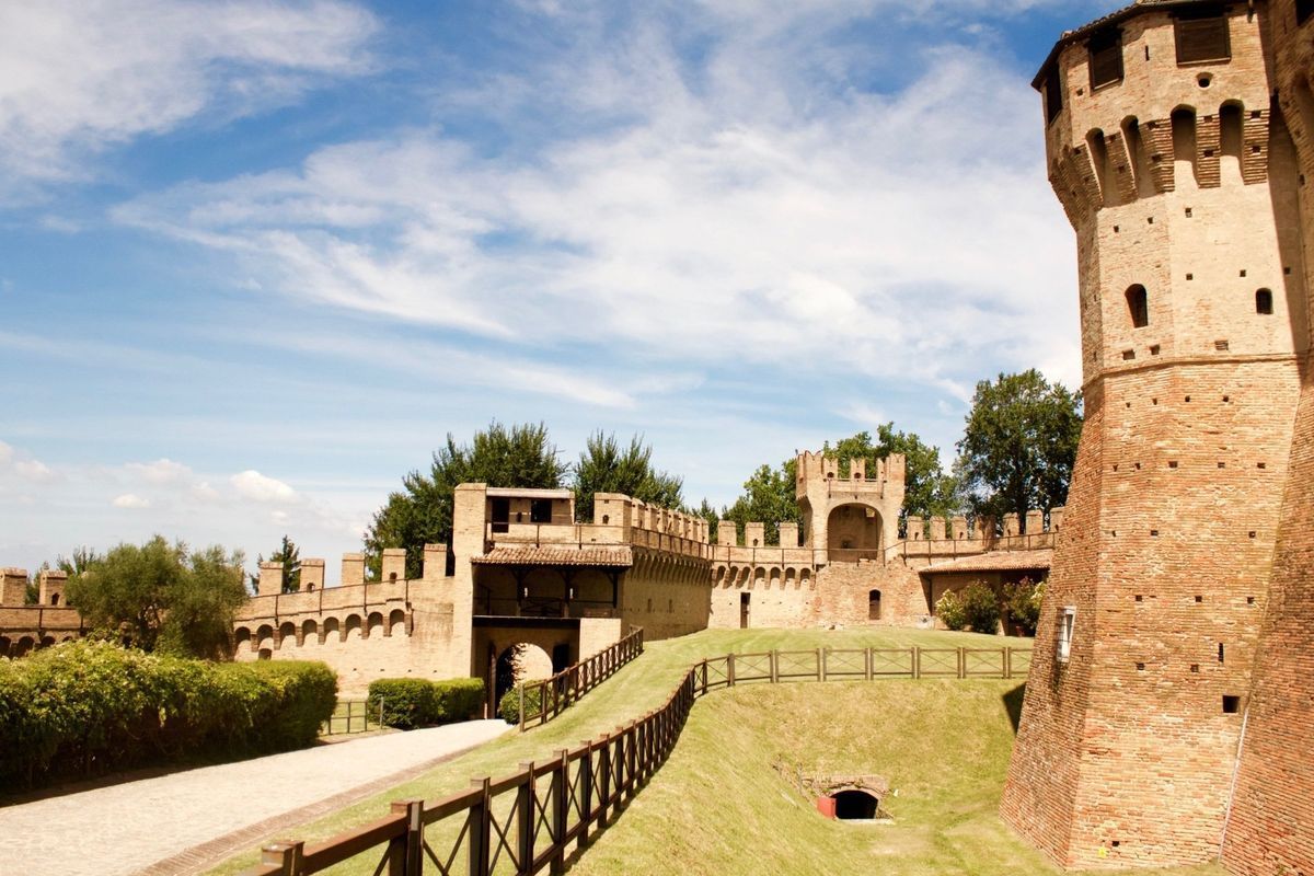 Stone castle walls and towers surrounding a grassy courtyard under a blue sky