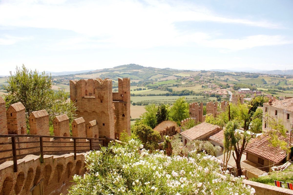 Stone castle ruins overlooking a sunny green valley and hills under a blue sky
