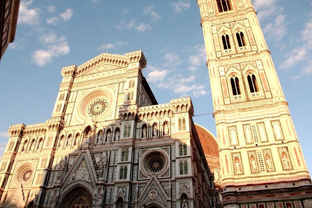 Historic cathedral facade and bell tower in warm evening light, likely Florence’s Duomo