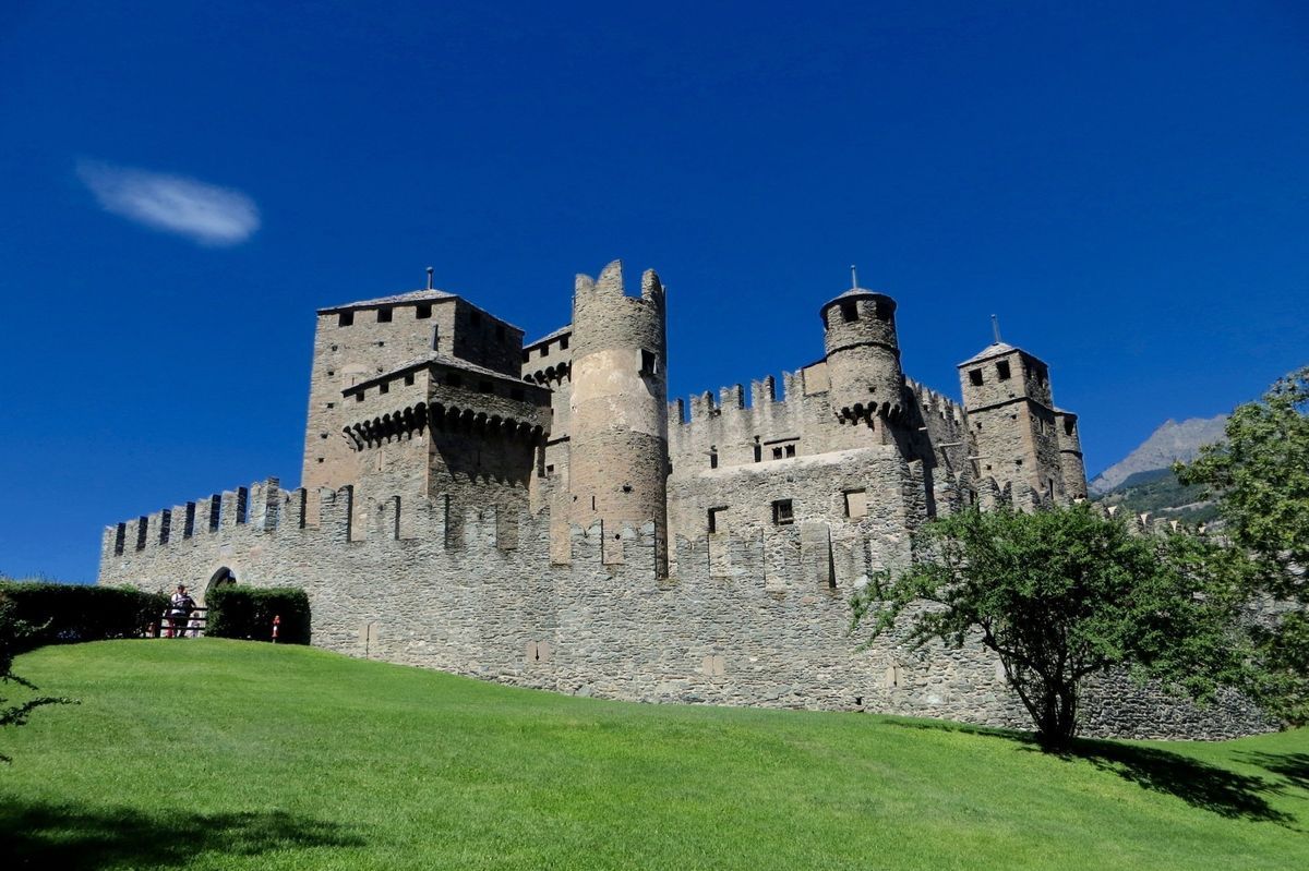 Stone castle on a green hill under a clear blue sky
