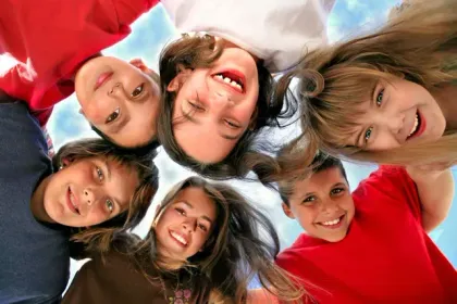 Smiling group in red and white shirts leaning in a circle, looking down at the camera