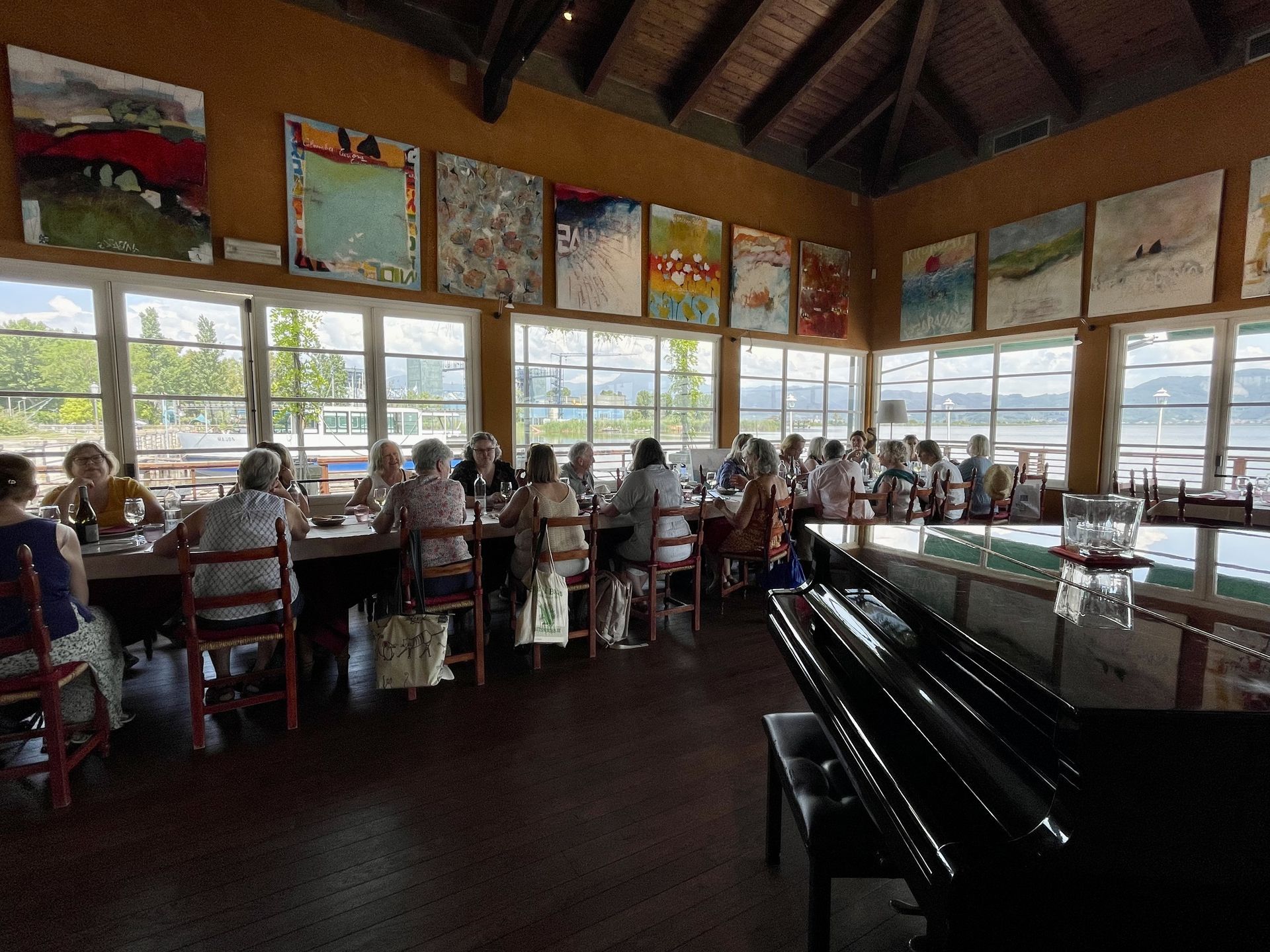 Restaurant dining room with diners seated by large windows and a piano in the foreground