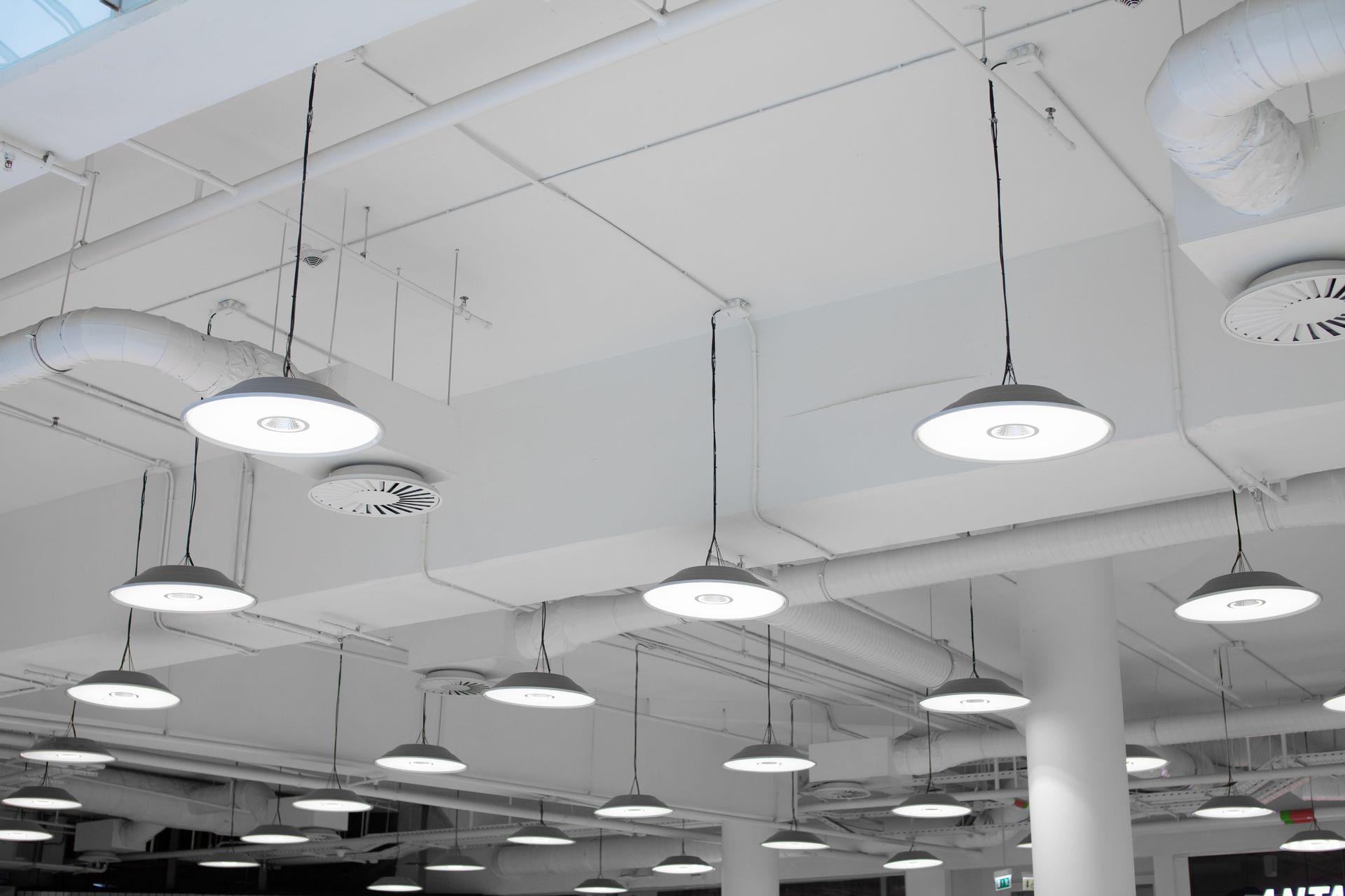 Suspended LED dome fixtures illuminating a commercial ceiling with exposed ductwork
