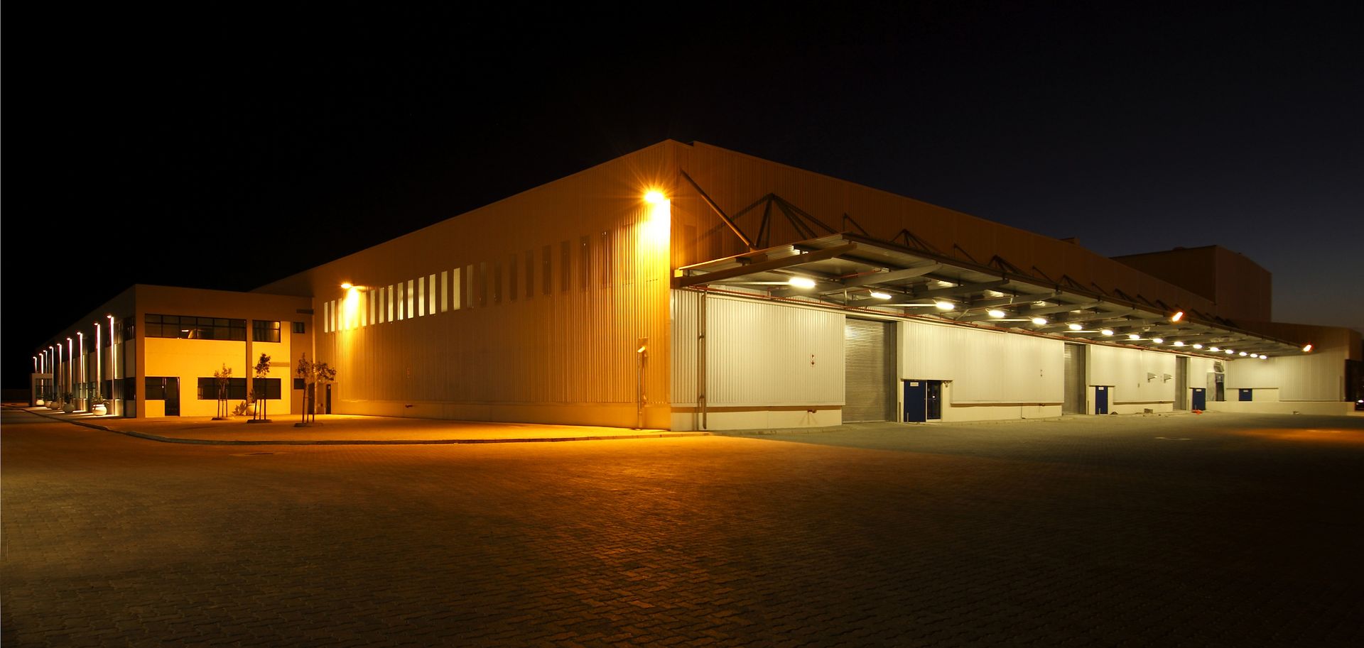 Commercial warehouse lit by exterior LED wall pack at night. Commercial warehouse lit by exterior LED wall pack at night.