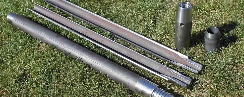 A bunch of metal pipes are sitting on top of a lush green field.