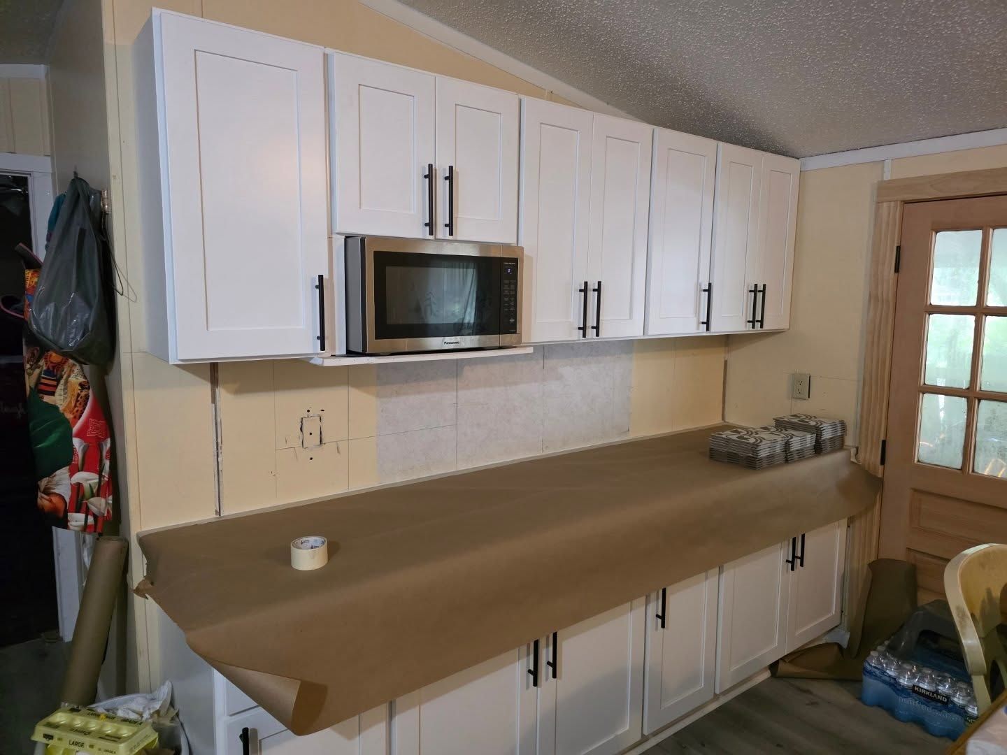 Kitchen with white cabinets, microwave, and brown countertops along one wall.