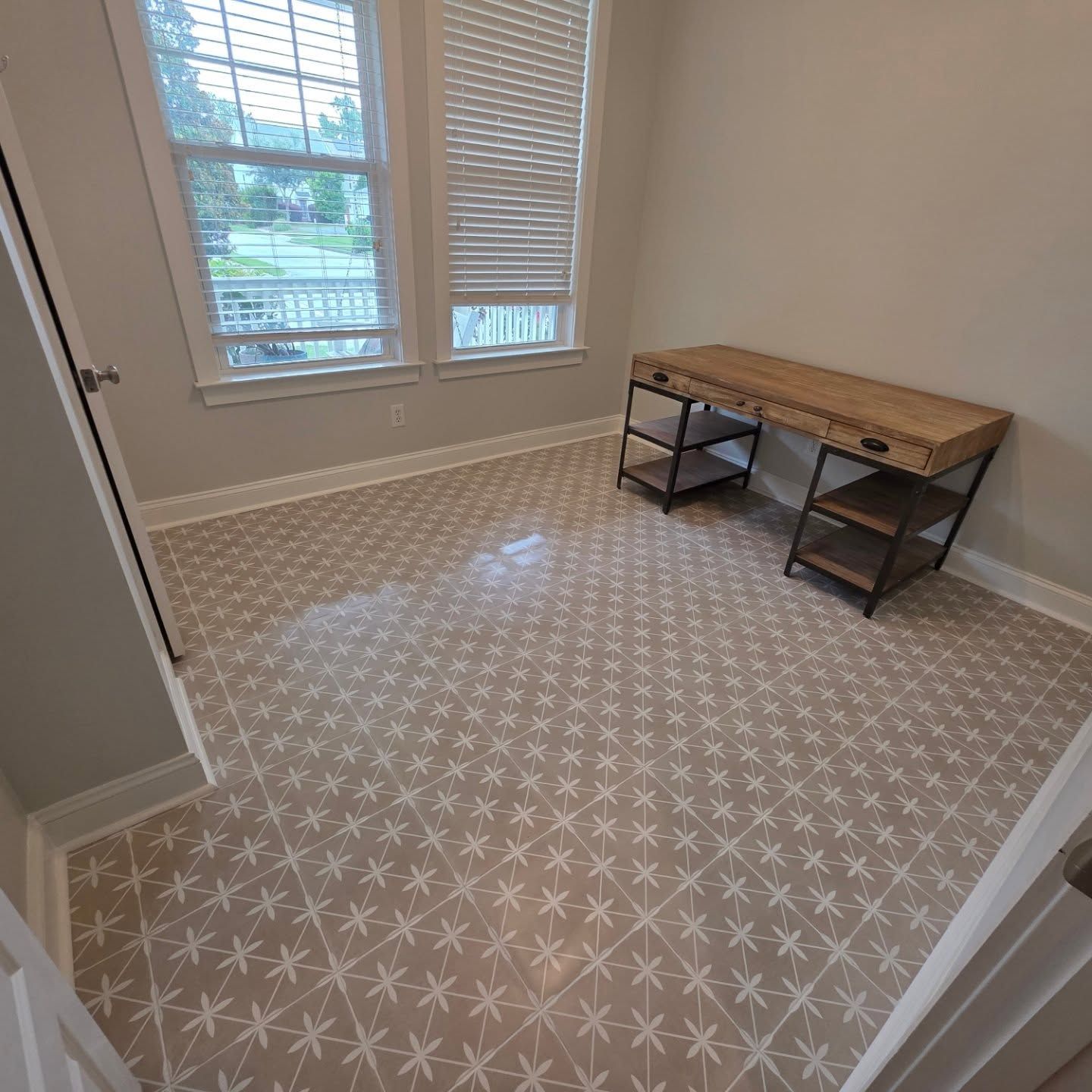 Empty carpeted room with large window and wood desk against the wall