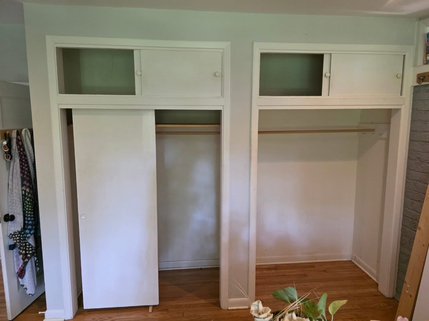 Open closet with white built-in shelves, hanging rods, and upper cubbies in a bedroom.