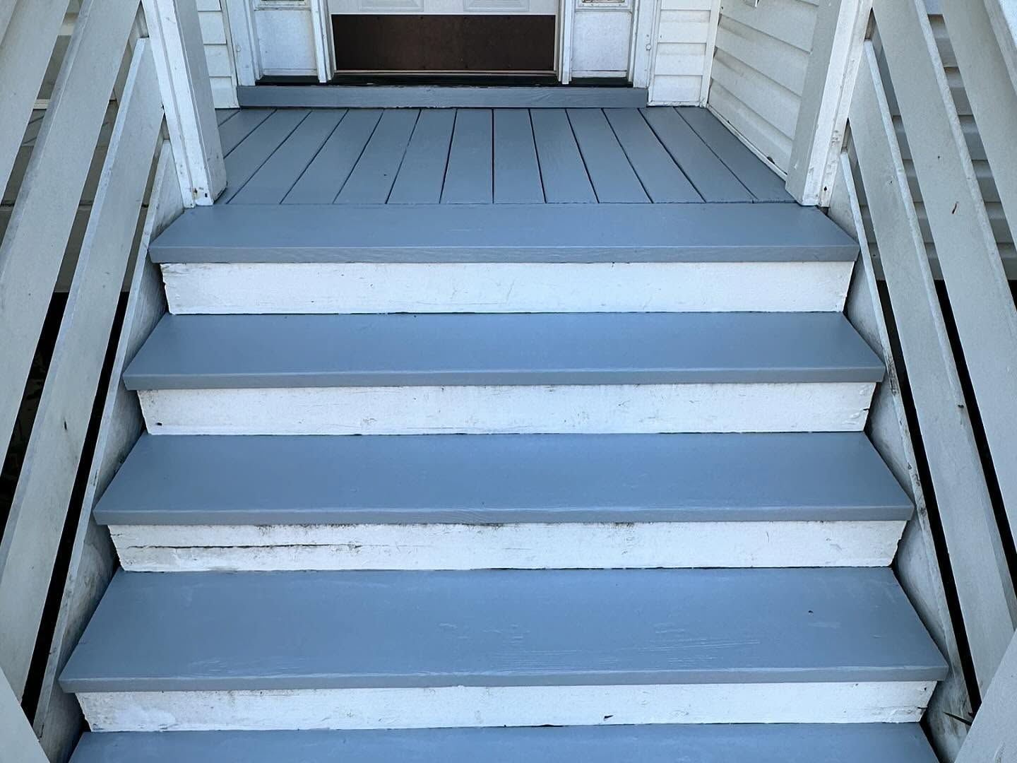 White-painted wooden porch steps leading to a doorway on a house exterior