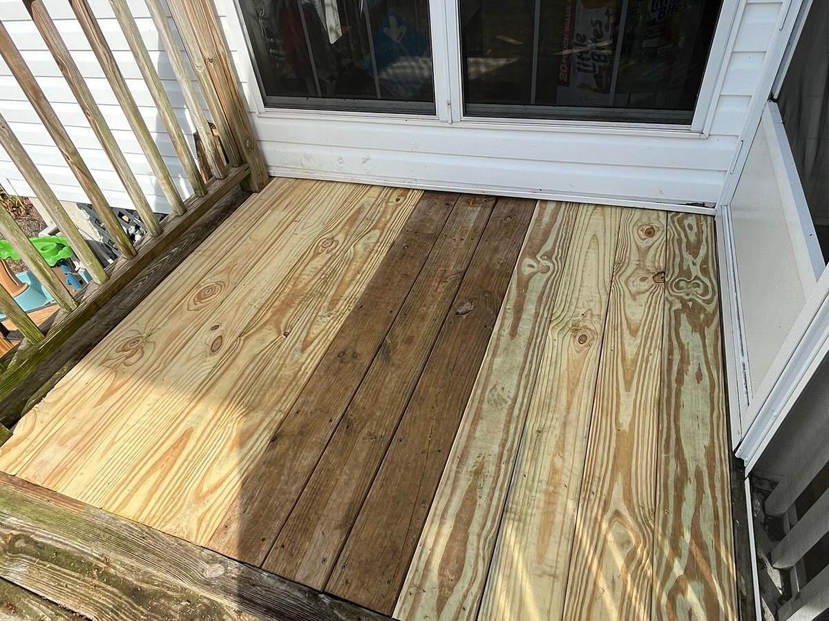 Weathered wooden porch deck with railings and a sliding glass door