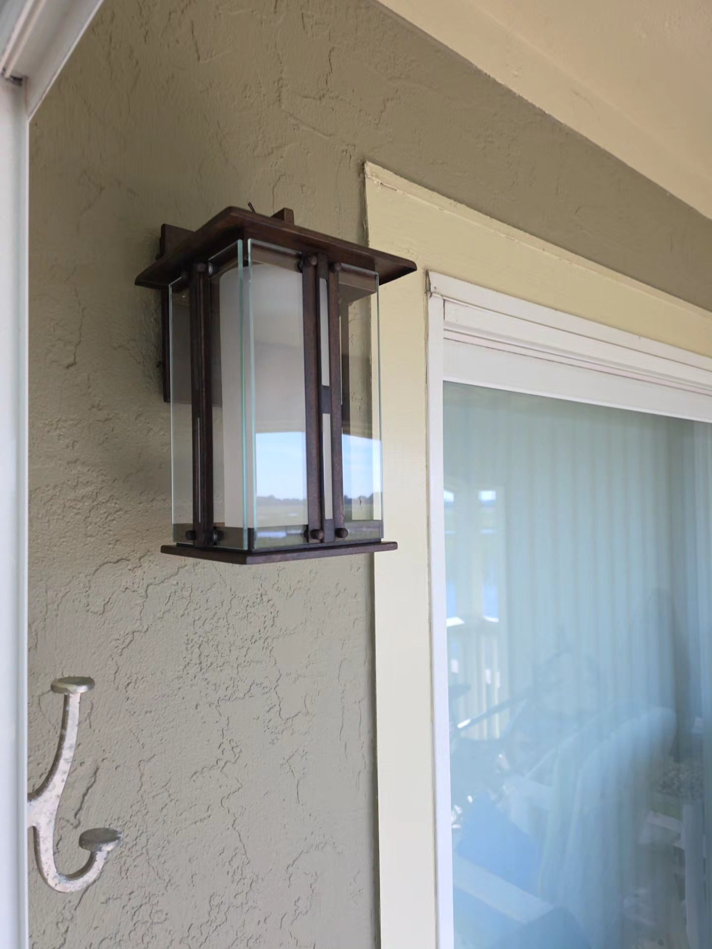 Outdoor wall lantern beside a window and beige stucco exterior wall