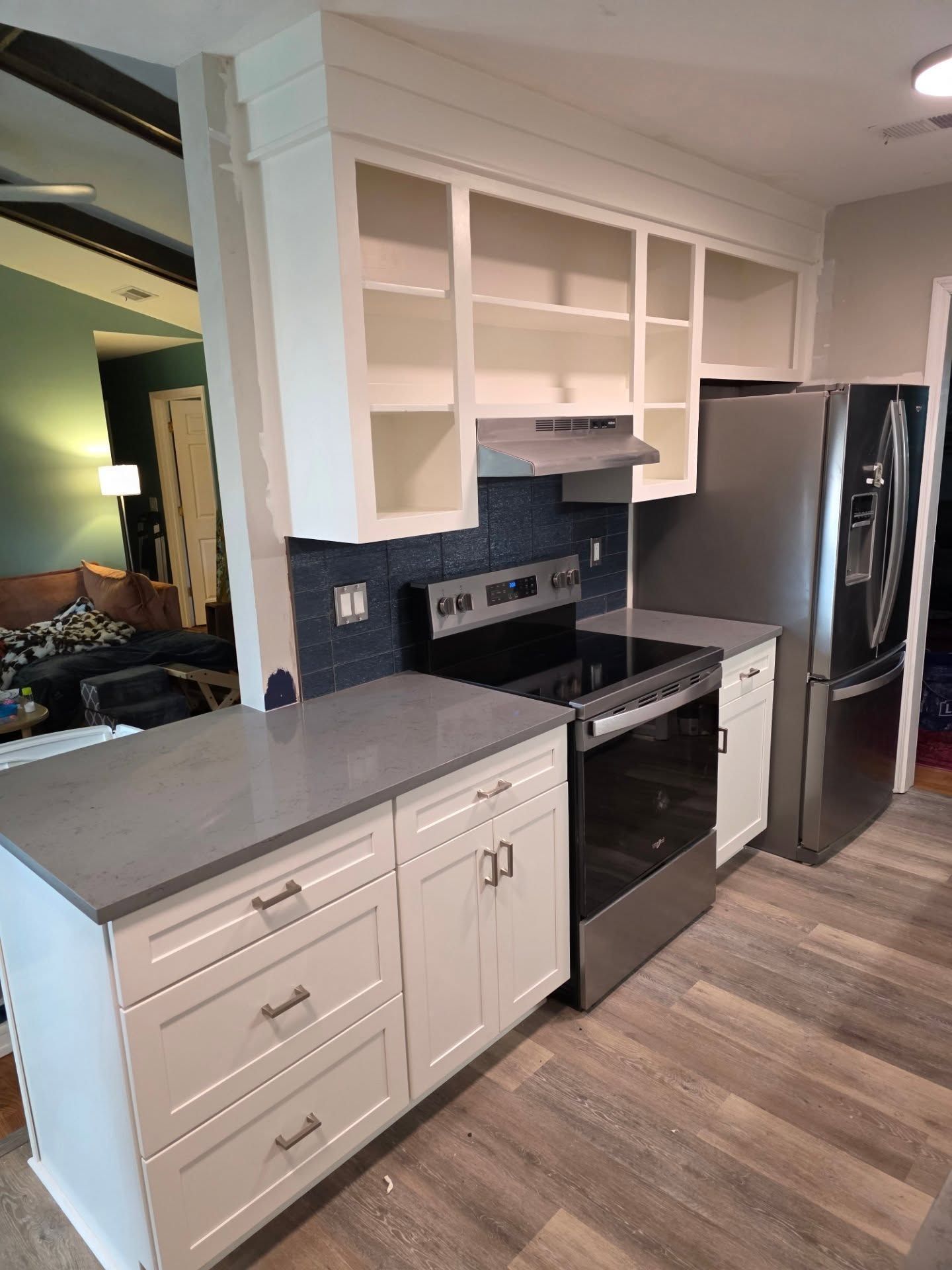 Modern kitchen with white cabinets, black stove, stainless fridge, and gray countertops.