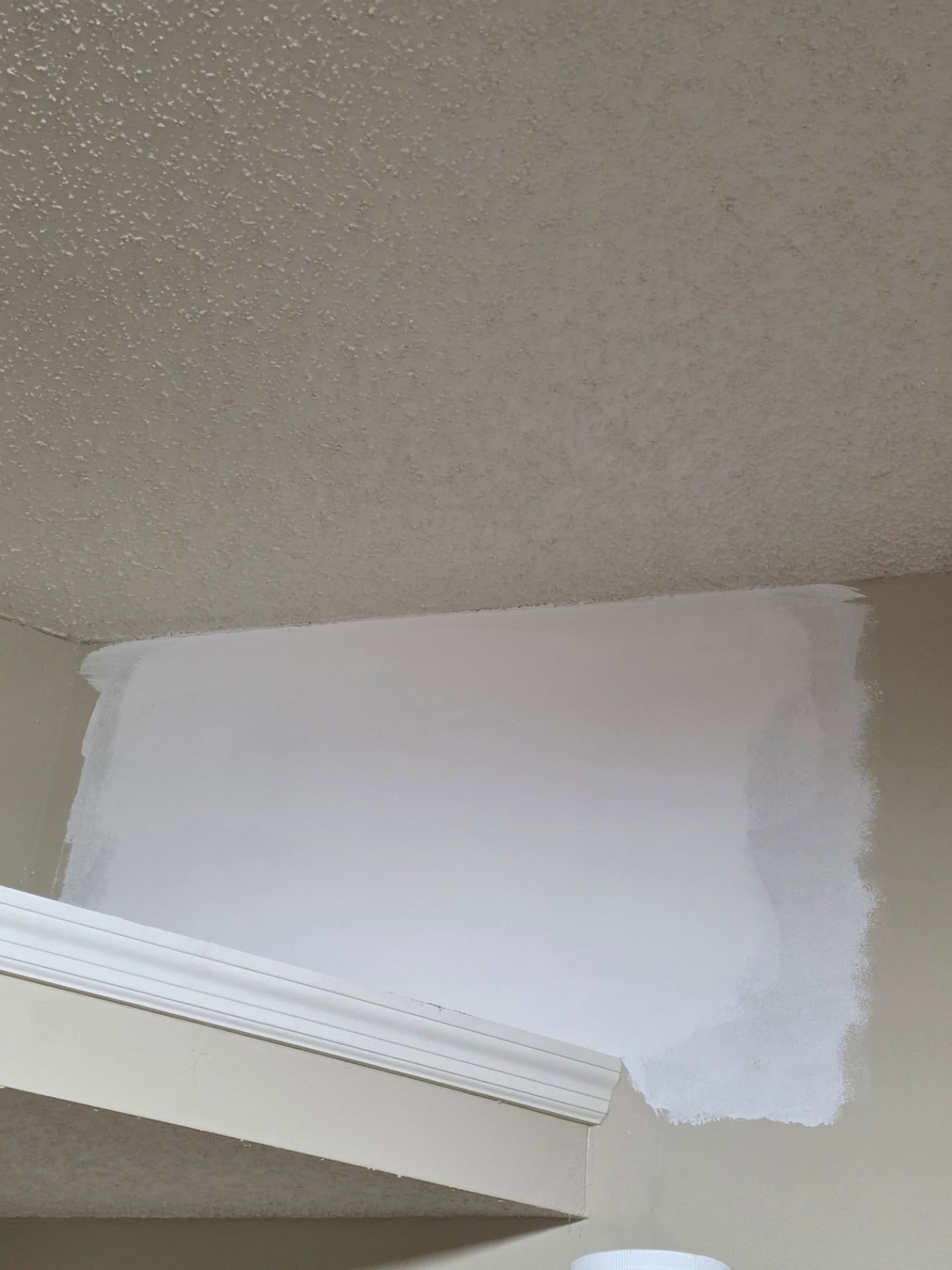 White patched wall area above a doorway under a beige ceiling