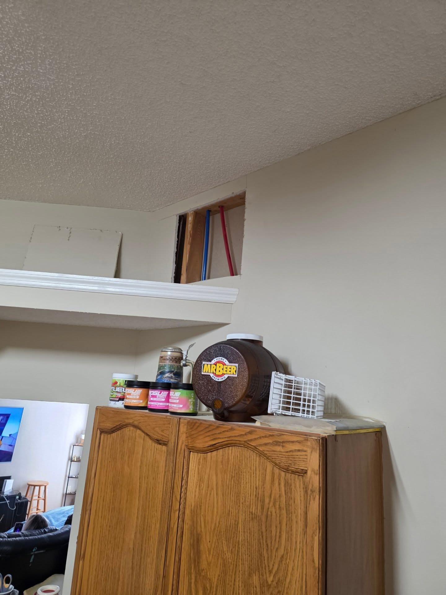 Bedroom corner with a wooden cabinet, shelf, and books in a cluttered room