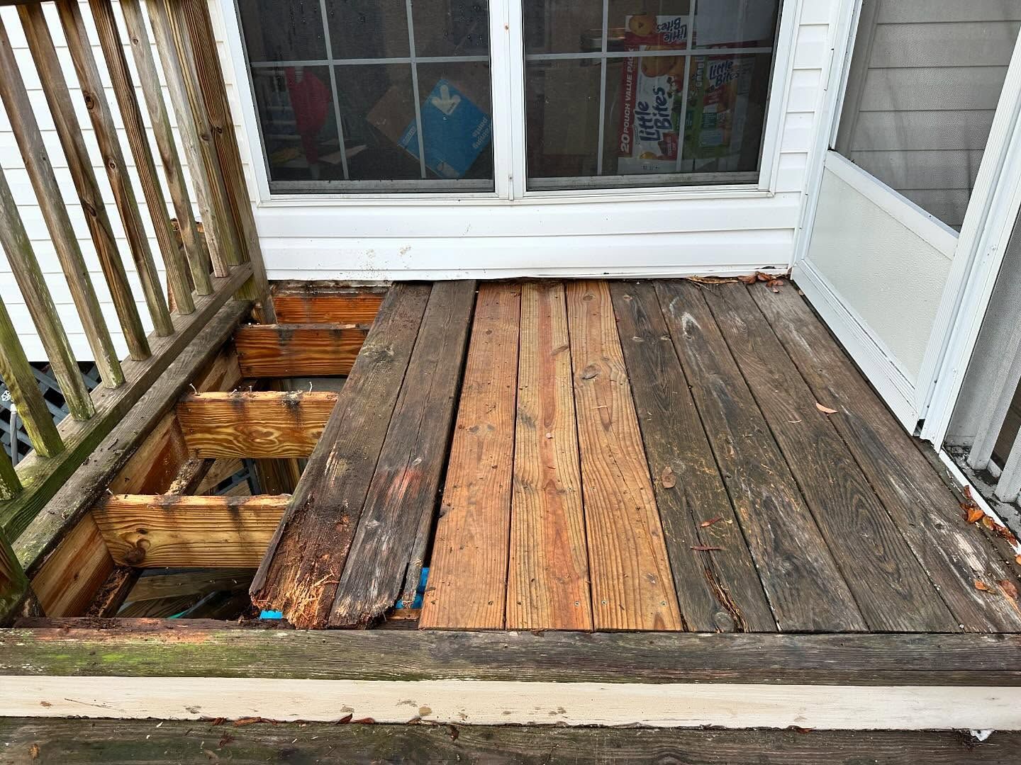 Weathered wooden deck with damaged, rotting boards near a white door and railing
