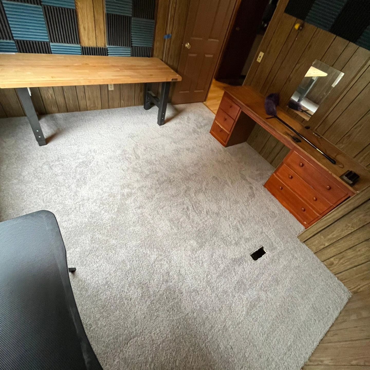 Small office with beige carpet, wooden desks, cabinets, and a chair in the foreground.