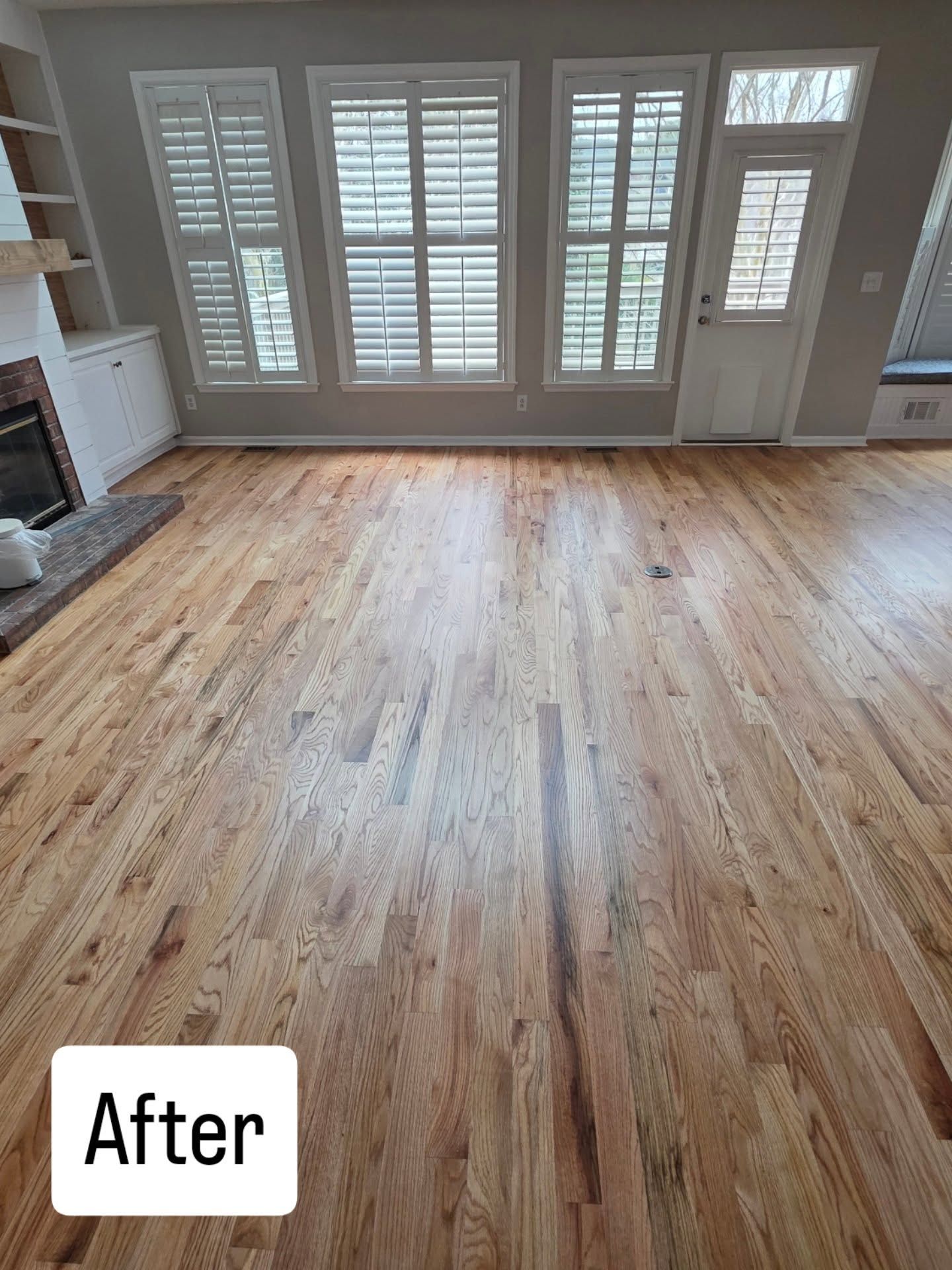 Empty room with refinished hardwood floors, white shutters, and an 