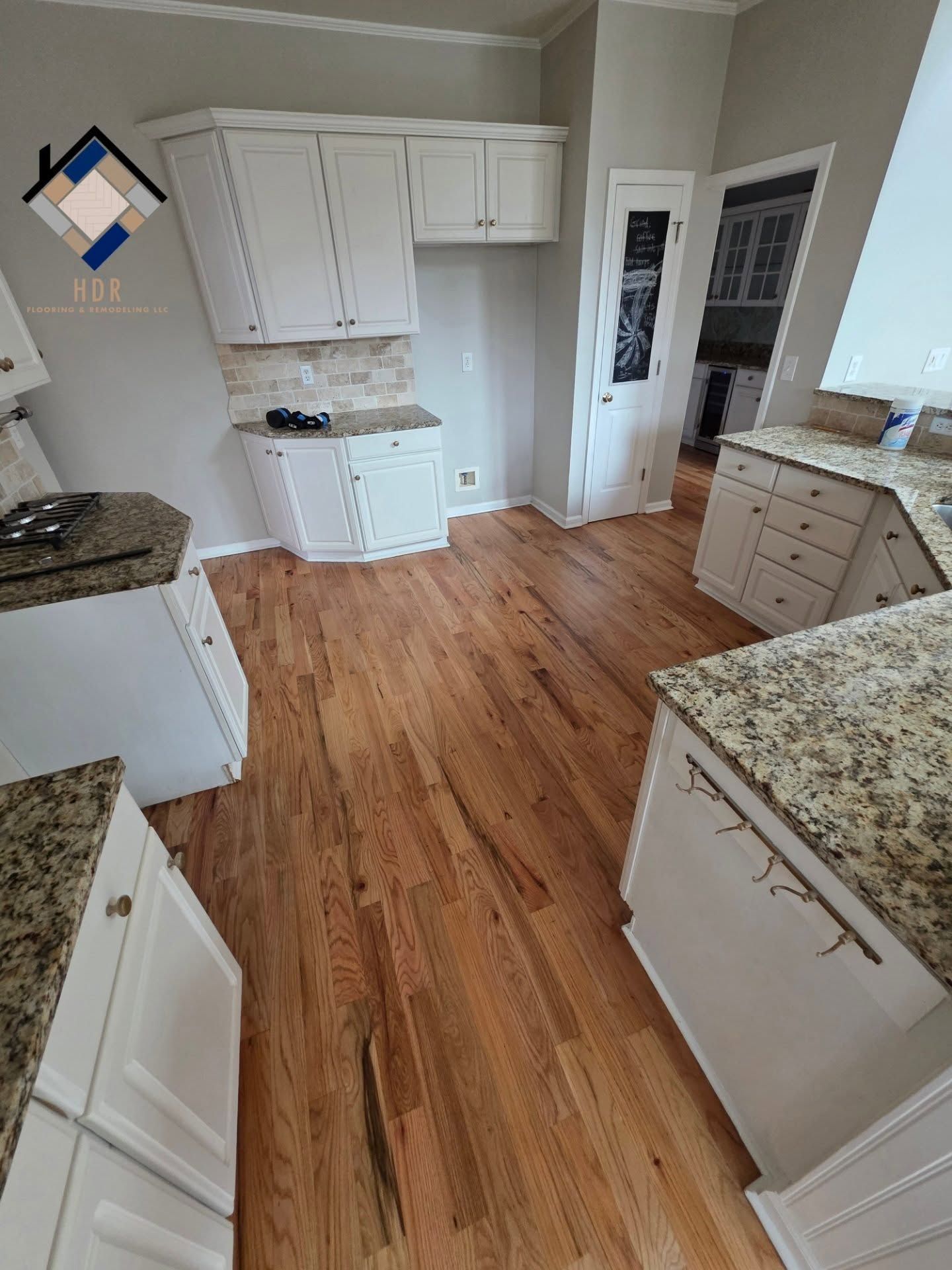 Bright kitchen with white cabinets, granite countertops, and hardwood floor.