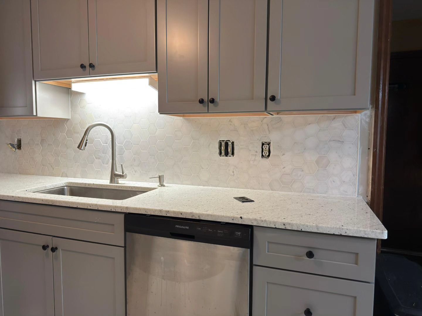 Modern kitchen with white cabinets, granite counters, sink, and stainless dishwasher
