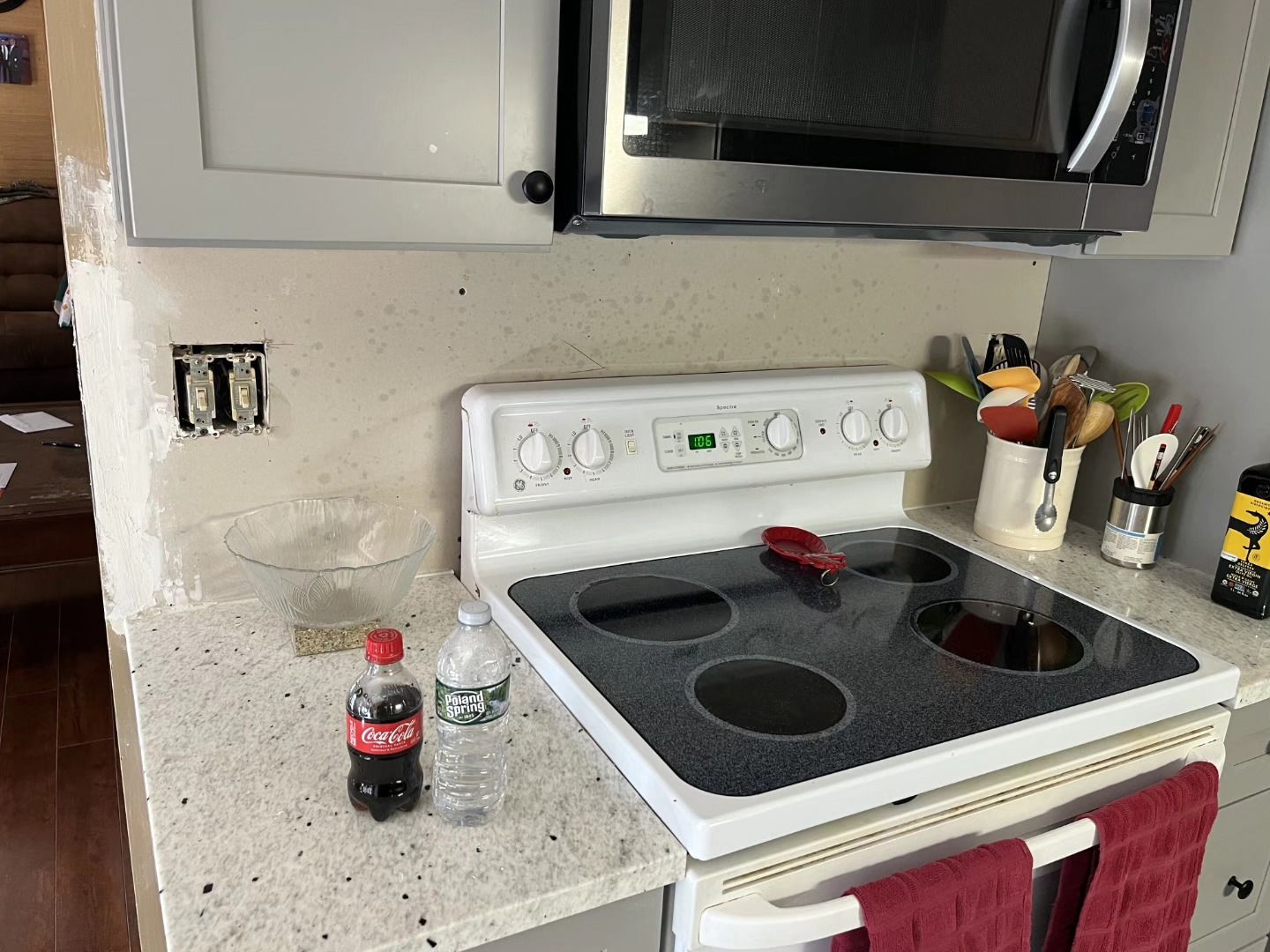 Kitchen stove with a Coca-Cola bottle, a water bottle, and utensils on a granite countertop