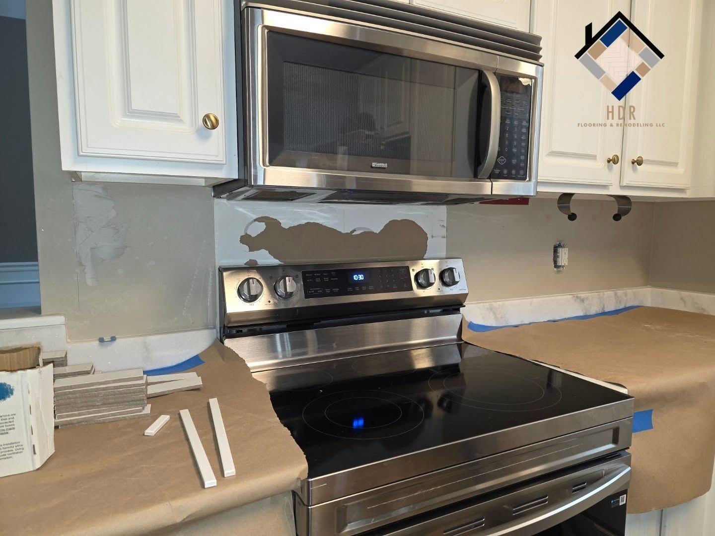 Kitchen stove and microwave with countertop covers and paint patches during renovation