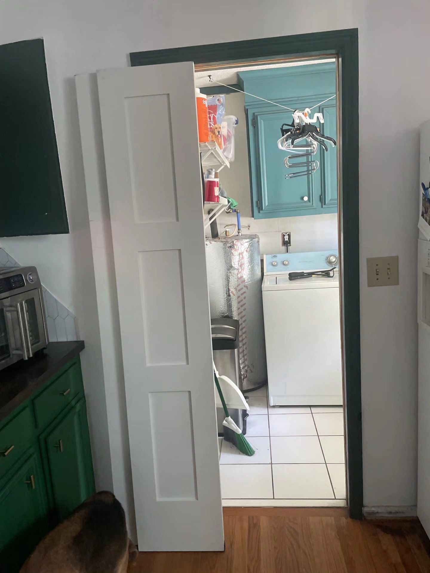 Open doorway into a small bathroom with teal walls, white sink, and shower fixtures.